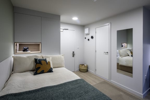a small bedroom with a bed and a mirror