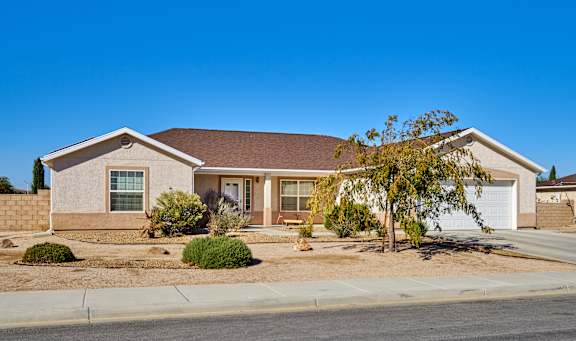A house with a brown roof and a tree in front.