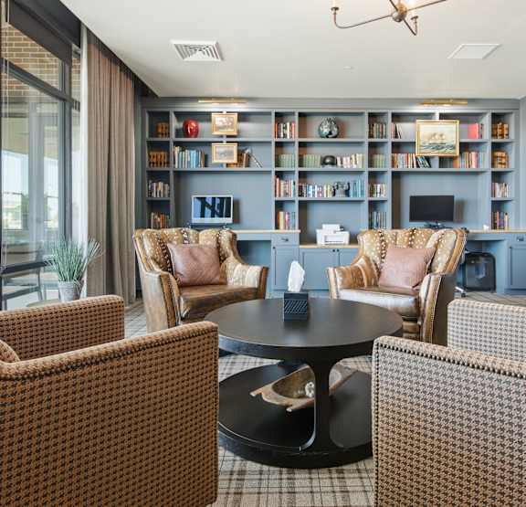 A modern living room with a black sofa, wooden coffee table, and a large mirror on the wall.