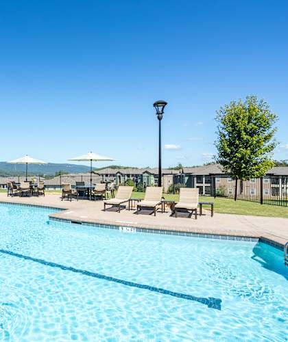 A large outdoor swimming pool with sun loungers and a view of the hills in the distance.
