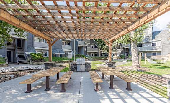 a picnic area with benches under a wooden pergola