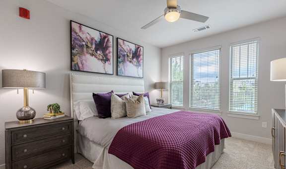 A bedroom with a bed, nightstand, and a ceiling fan.