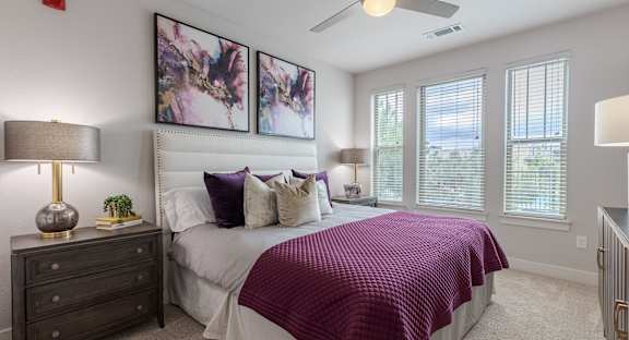 A bedroom with a bed, nightstand, and a ceiling fan.