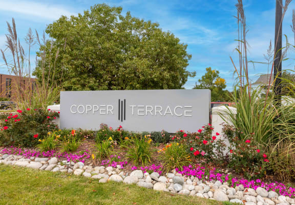 a sign for cooper terrace in front of flowers and trees