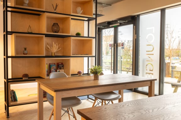 a dining area with a wooden table and chairs and a bookshelf