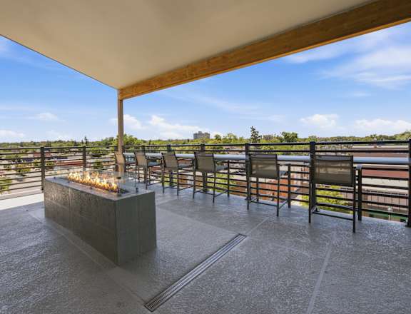 A patio with a fire pit and chairs overlooking a body of water.