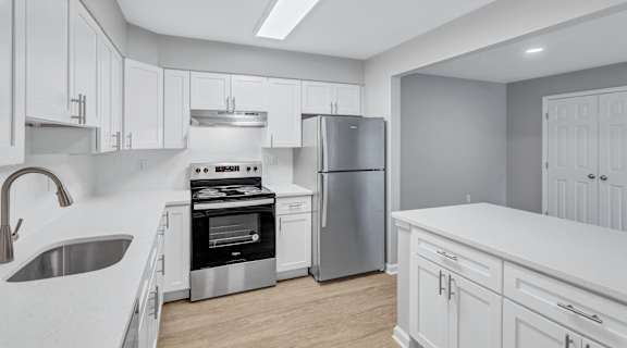 a large kitchen with white cabinets and stainless steel appliances