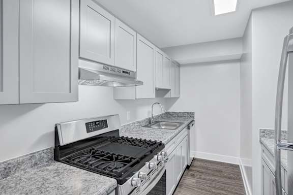 A kitchen with a black countertop and white cabinets.