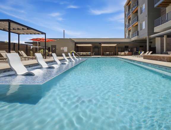 A long rectangular pool with white sun loungers on either side.