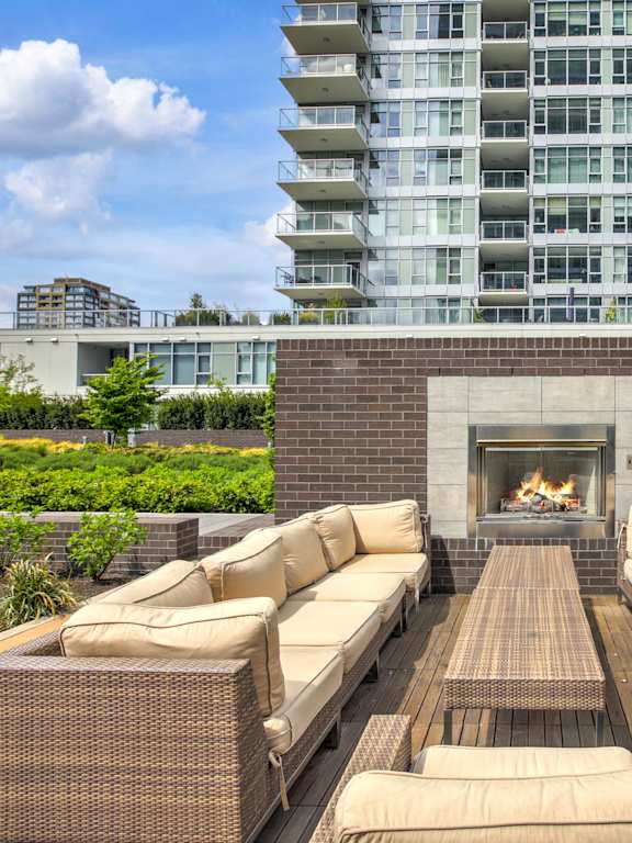 A patio with a fireplace and seating area in front of a modern building.