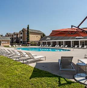 a swimming pool with lounge chairs and umbrellas in front of a building
