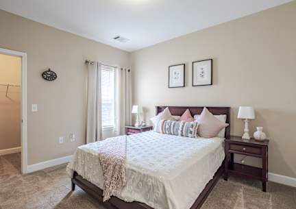 a bedroom with a bed and two nightstands and a window