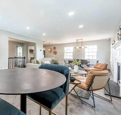 an open living room with a round table and chairs and a kitchen with a table