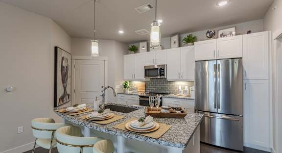 A modern kitchen with a dining table set for two.
