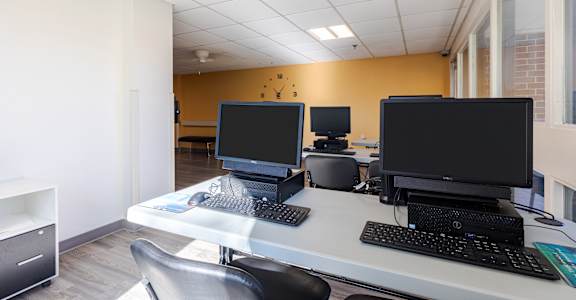 A white desk with two monitors and a keyboard.