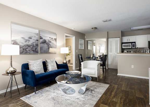 A living room with a blue couch and a grey rug.