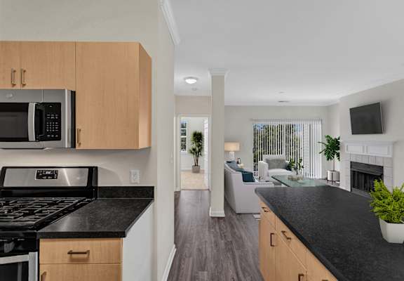 A modern kitchen with black countertops and wooden cabinets.