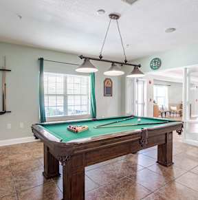 a pool table in a game room with lights on the ceiling