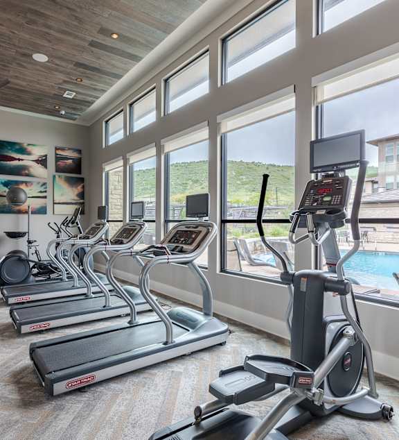 A gym with treadmills, elliptical machines, and a weight rack.