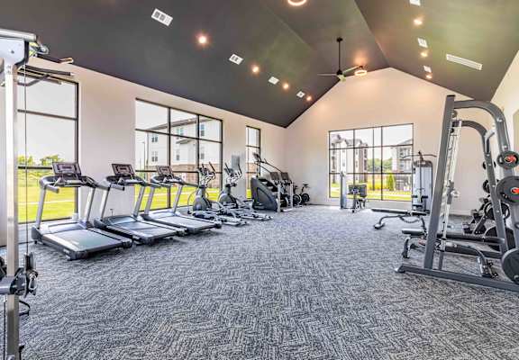 a gym with cardio equipment and windows in a building