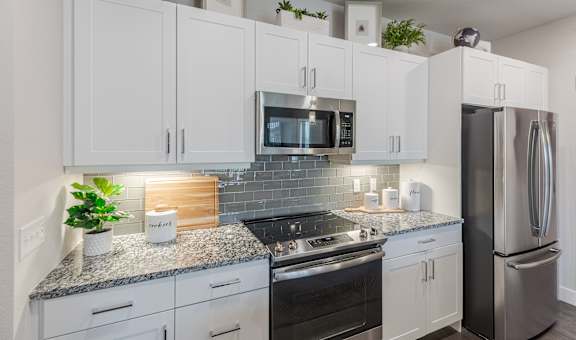 A kitchen with white cabinets and a granite countertop.