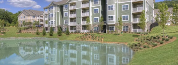 an apartment building with a pond in front of it
