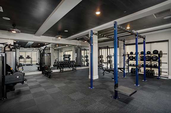 A gym with a variety of equipment including weights and a bench.