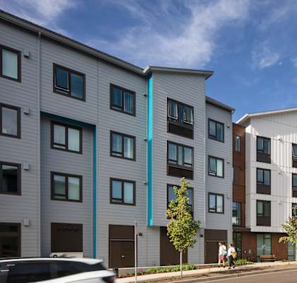 A modern apartment building with a white exterior and blue accents.