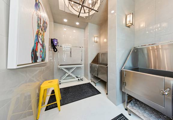 a white bathroom with a stainless steel sink and a yellow stool