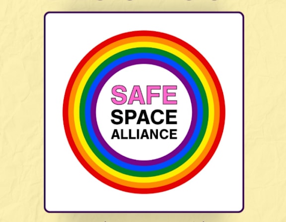 A sign with a rainbow and the words "Safe Space Alliance" written on it.