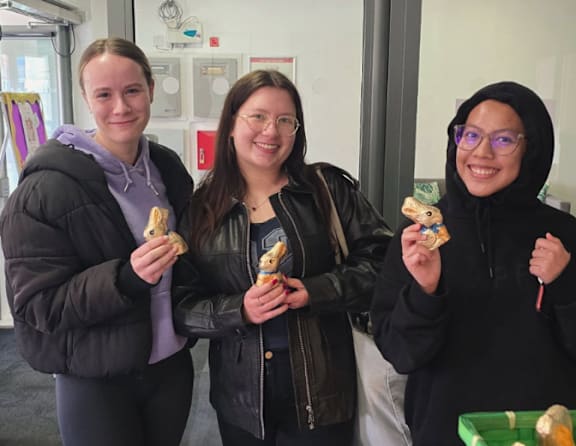 Three people holding food items in their hands.