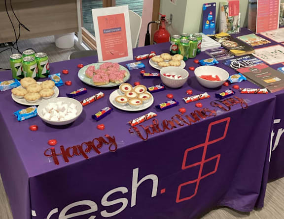 A table with a purple cloth and a sign that says Happy Birthday.