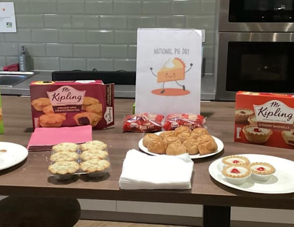 A table with a sign that says National Pie Day and several boxes of M&K pie.