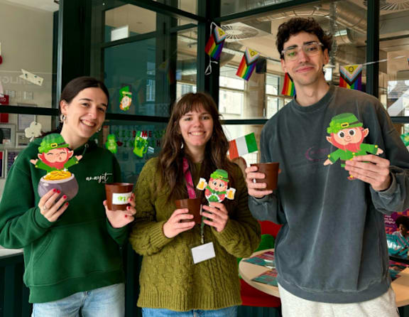 Three people holding cups with elf designs on them.