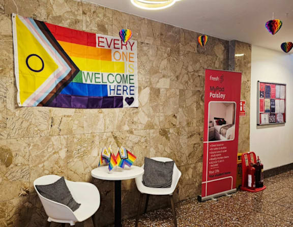 A room with a rainbow flag and a sign that says "Everyone is welcome here".