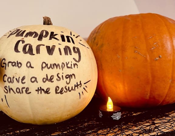 A pumpkin carving activity with a pumpkin and a candle on a table.