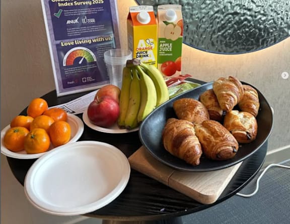 A breakfast spread with croissants, fruit, and juice on a table.