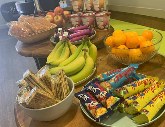 A table full of food including bananas, oranges, and crackers.