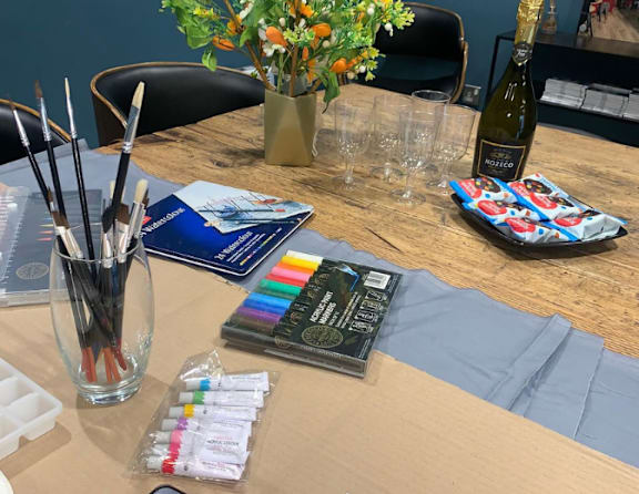 A table with a bottle of Moet champagne, a glass, and some art supplies.