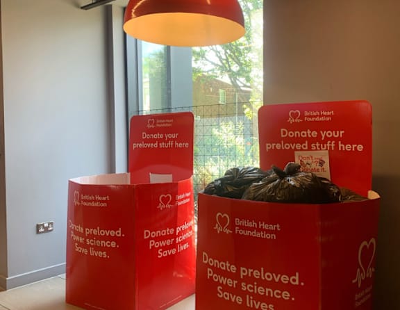Three red bins with the words "Donate your preloved stuff here" and "British Heart Foundation" on them.