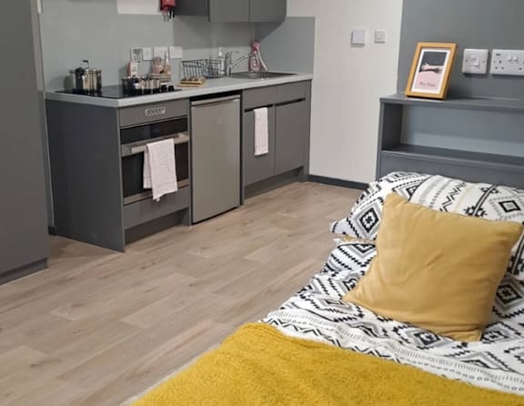 A kitchen with a yellow rug in front of a bed.
