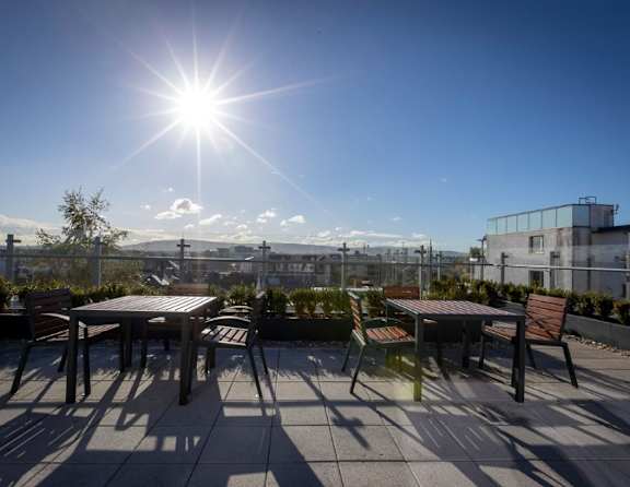 A sunny day on a rooftop with tables and chairs.