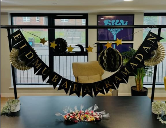 A table with a sign that says Eid Mubarak and a bowl of candy.