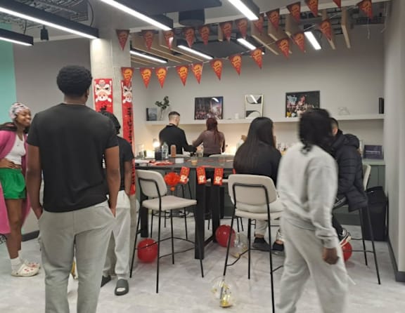A group of people are gathered in a room with orange bunting.