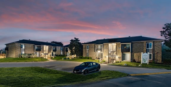 a car parked in front of an apartment building at sunset