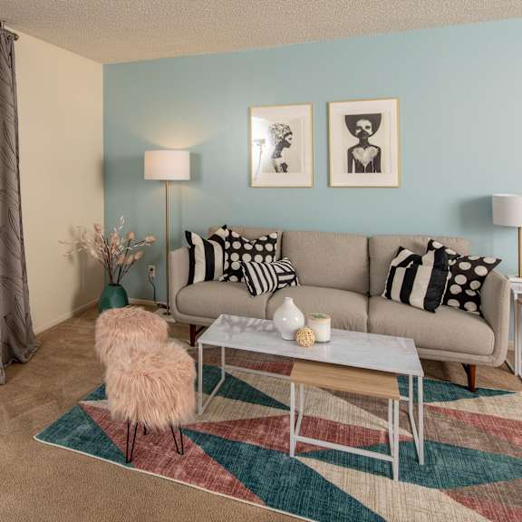 A living room with a grey couch, a round table, and a television.