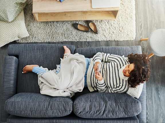Woman is lying on a grey couch at Wheelhouse Lofts, Dayton, 45402