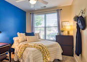 Thumbnail 4 of 4 - A bedroom with a bed, nightstand, and chair.