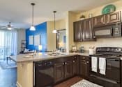 Thumbnail 3 of 4 - A kitchen with dark brown cabinets and a black stove top oven.