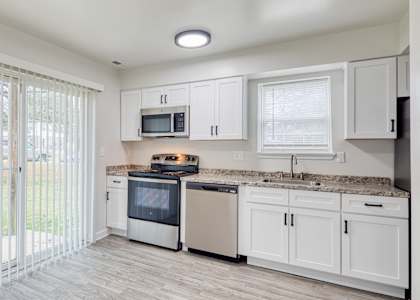 a kitchen with white cabinets and a sliding glass door